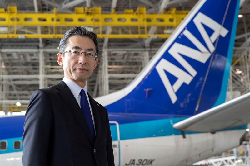 Yuji Hirako, CEO, ANA standing in a hangar in front of an ANA airplane.